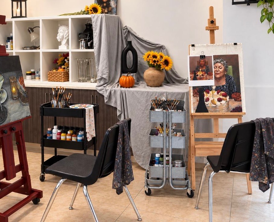 Sunlit art studio with easels, art supplies, and a shared worktable